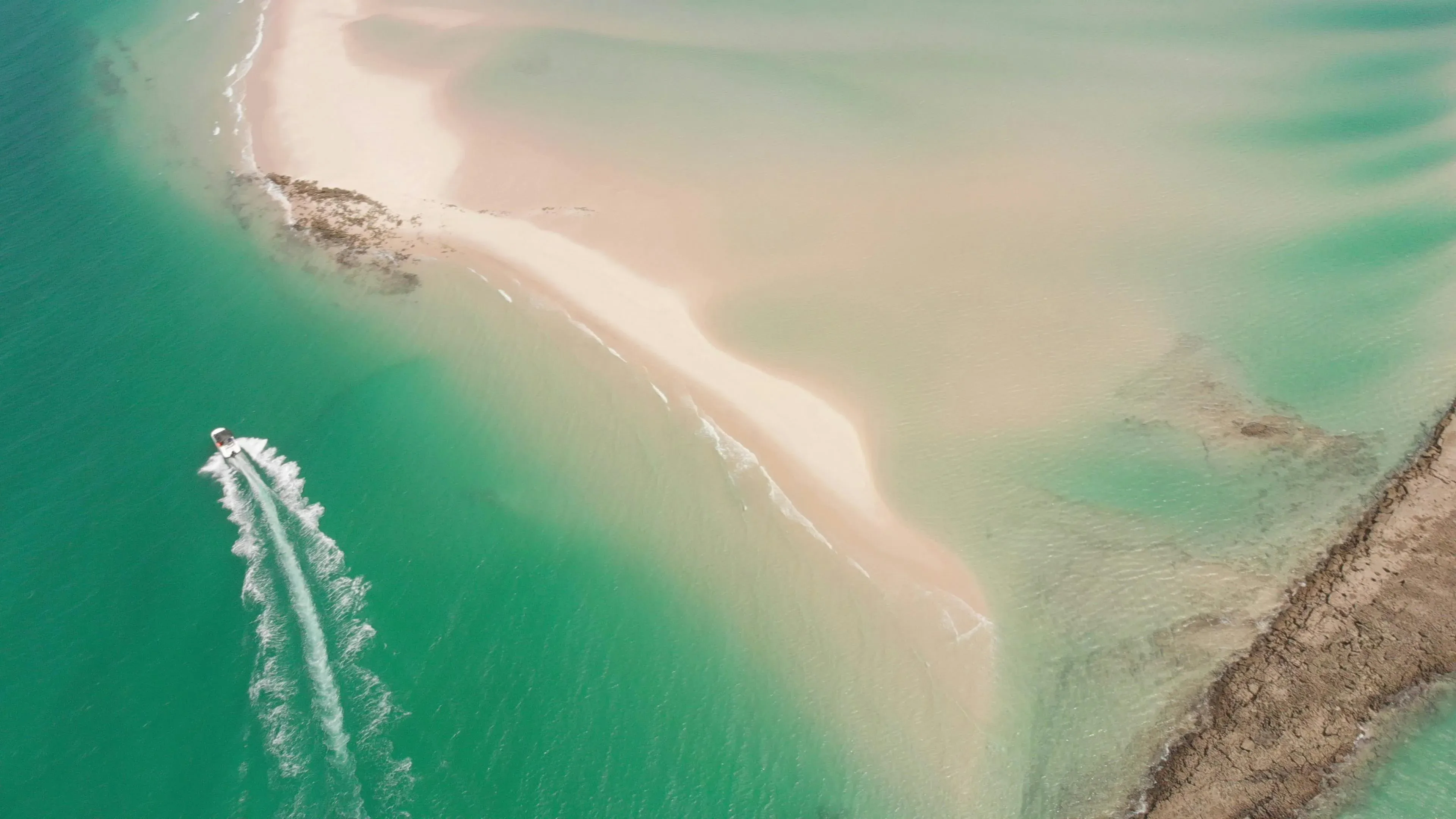Aerial view of a boat carving a wake past a sandbar on Moreton Bay, Brisbane
