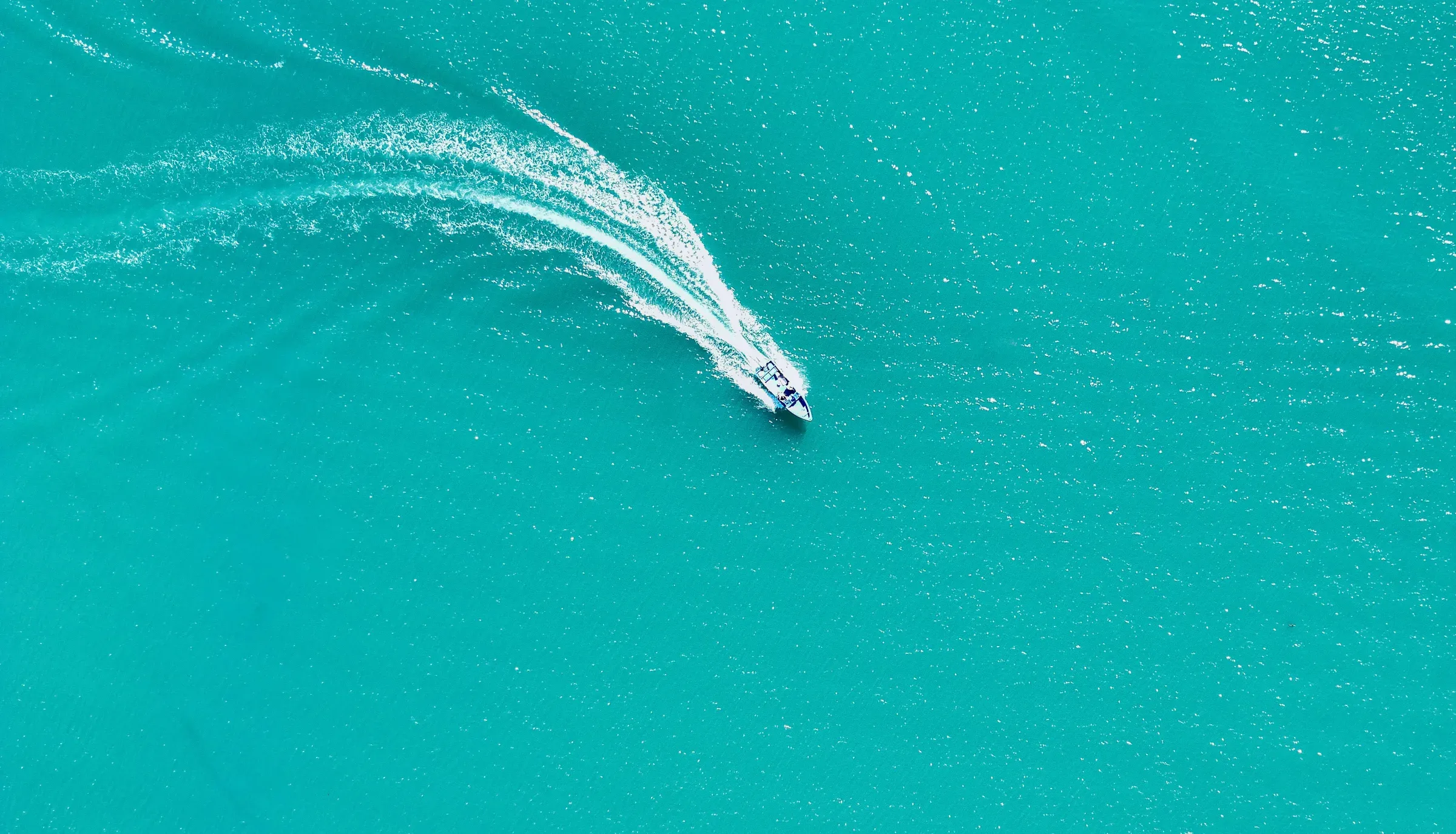 A boat carving a turn across clear turquoise water