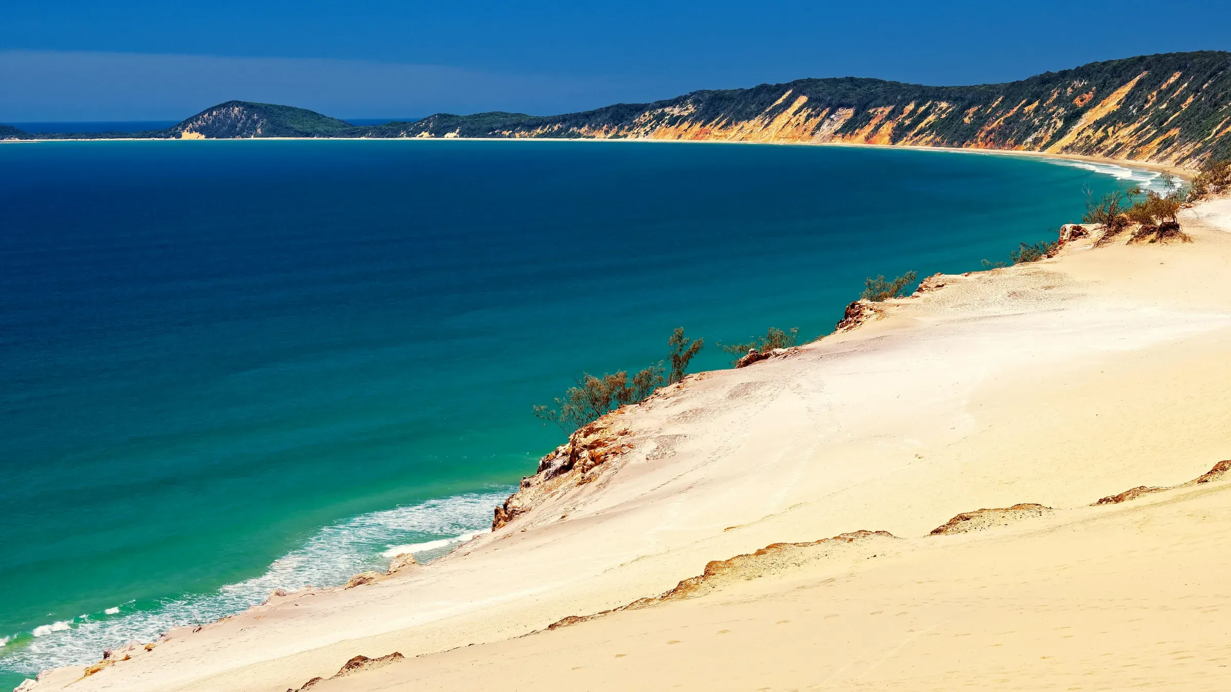 Coloured sand cliffs above turquoise water on a sweeping Sunshine Coast beach